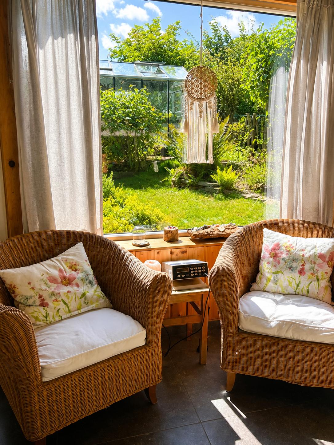 Sitzecke mit Rattansesseln und Blick in den Garten